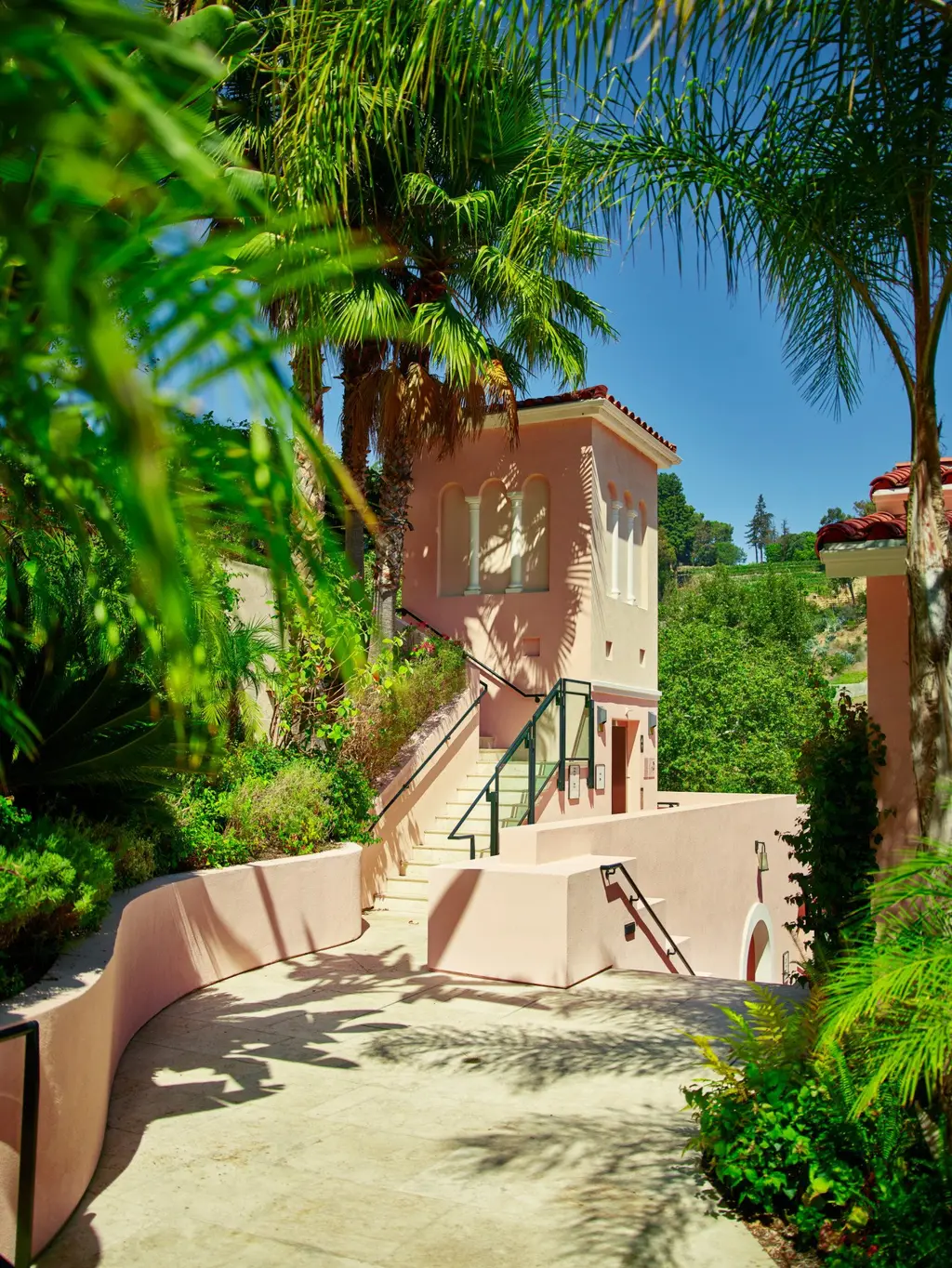 A pink stairway climbing through the plants towards the rooms