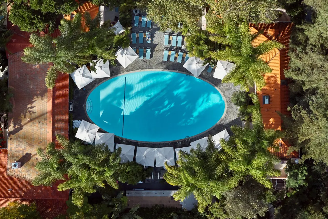 The oval pool from above, white umbrellas and trees all round