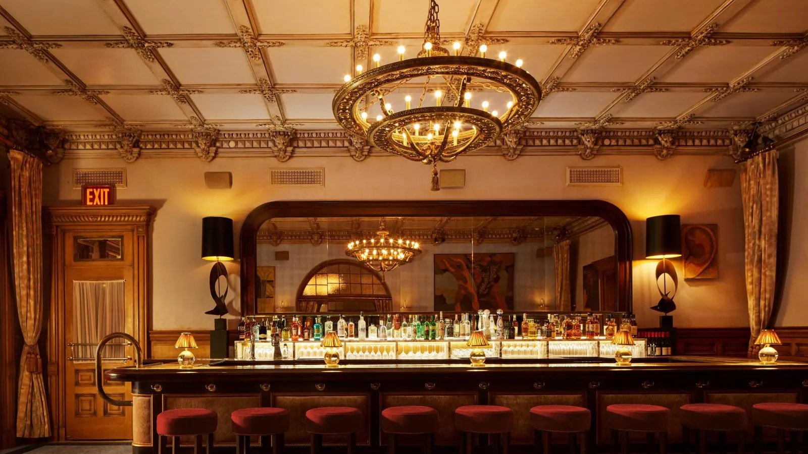 The Lobby Bar counter under the chandelier, its coffered ceiling and red stools