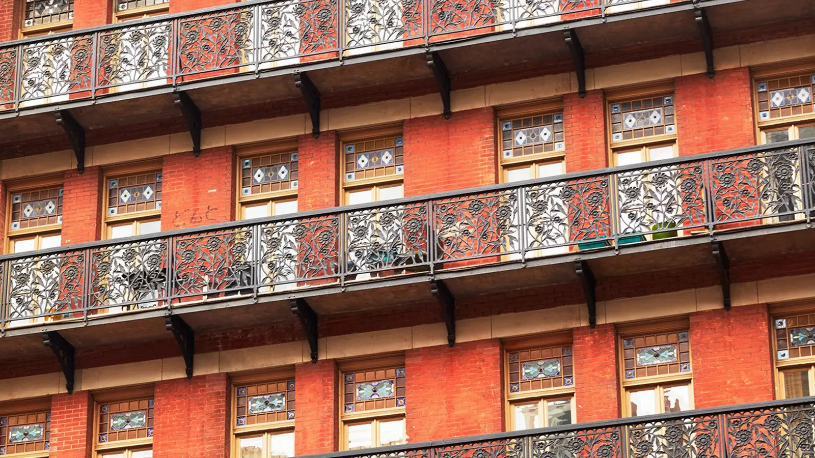 The façade’s wrought-iron balconies, floor above floor, against the red brick