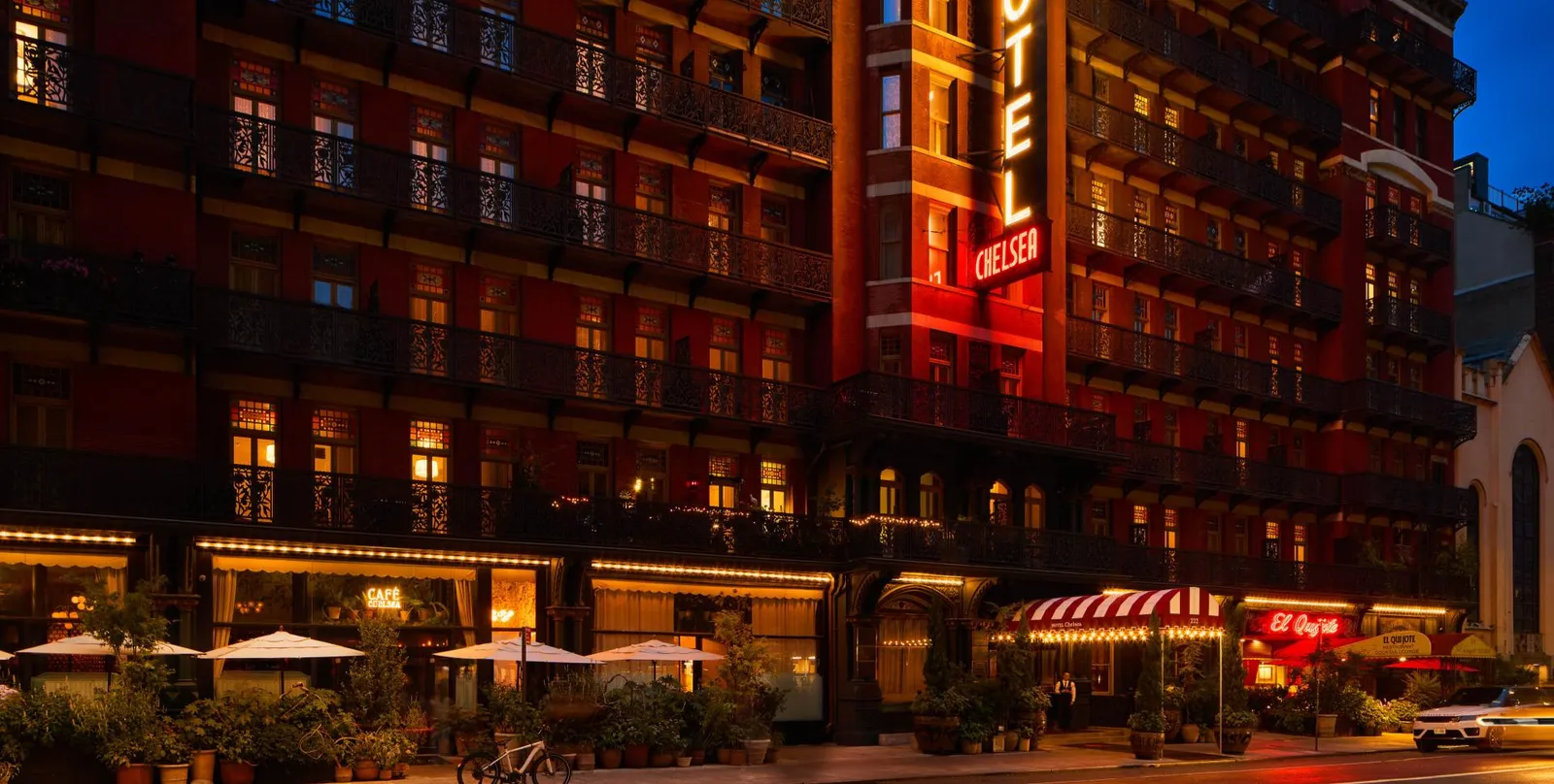 Hotel Chelsea’s red-brick façade at night, with its vertical neon sign