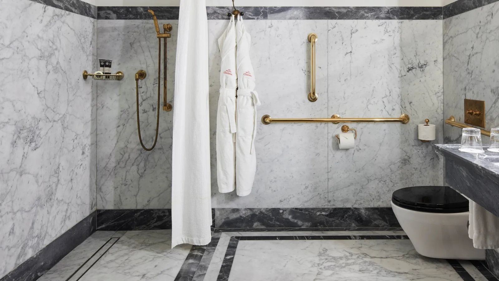 The marble bathroom of the accessible room, with its roll-in shower and brass grab rails