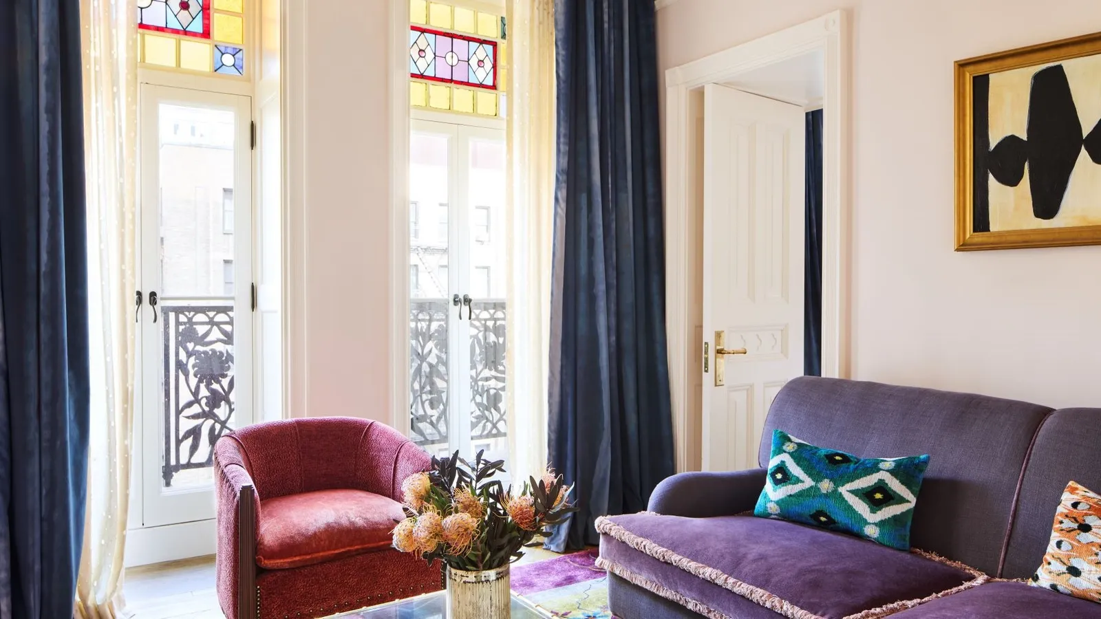 A Petite Suite living room, the purple sofa facing the doors onto the Juliet balcony
