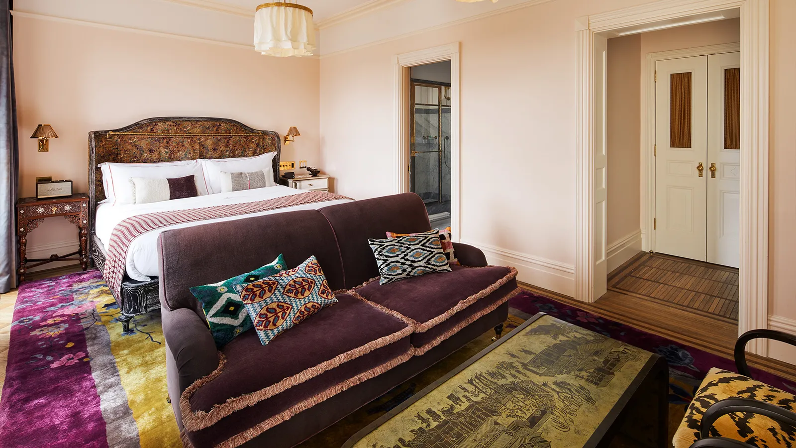 A Premier Chelsea with the bed, a purple sofa and a magenta rug