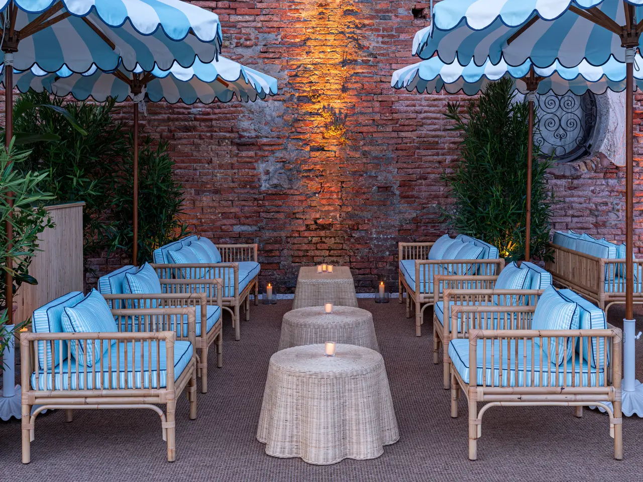 Bacaro Dior’s blue-striped bamboo sofas under scalloped parasols against a brick wall.