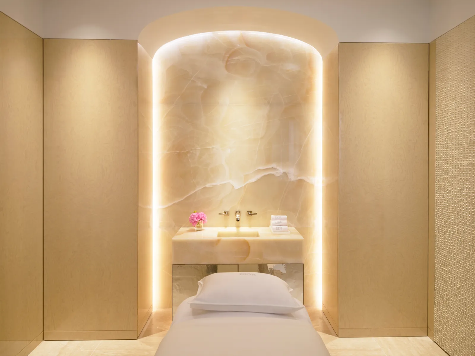 A Dior Spa treatment room: the couch before a backlit onyx niche with a stone basin.