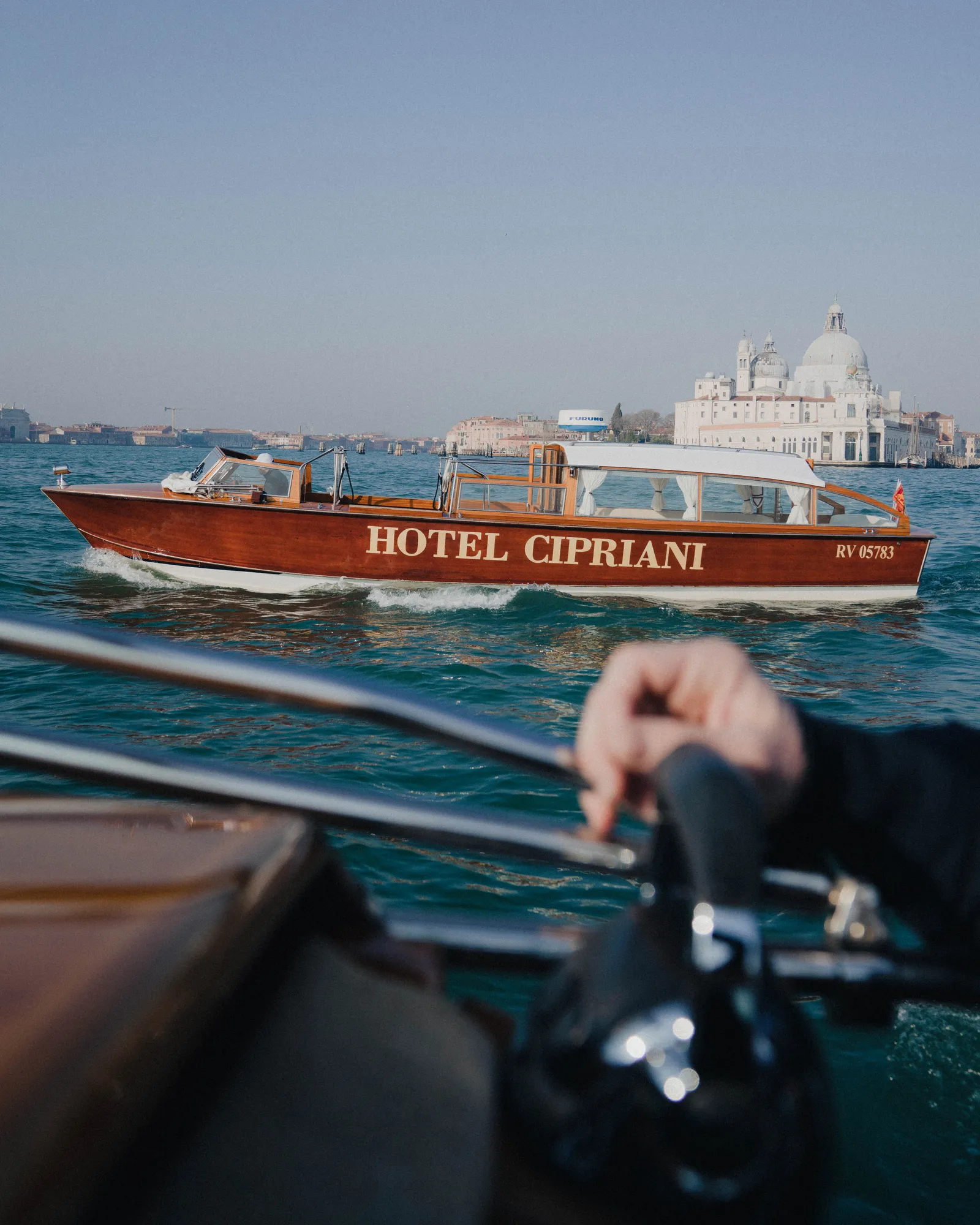 The wooden launch lettered Hotel Cipriani crosses the basin, the basilica of the Salute behind it.