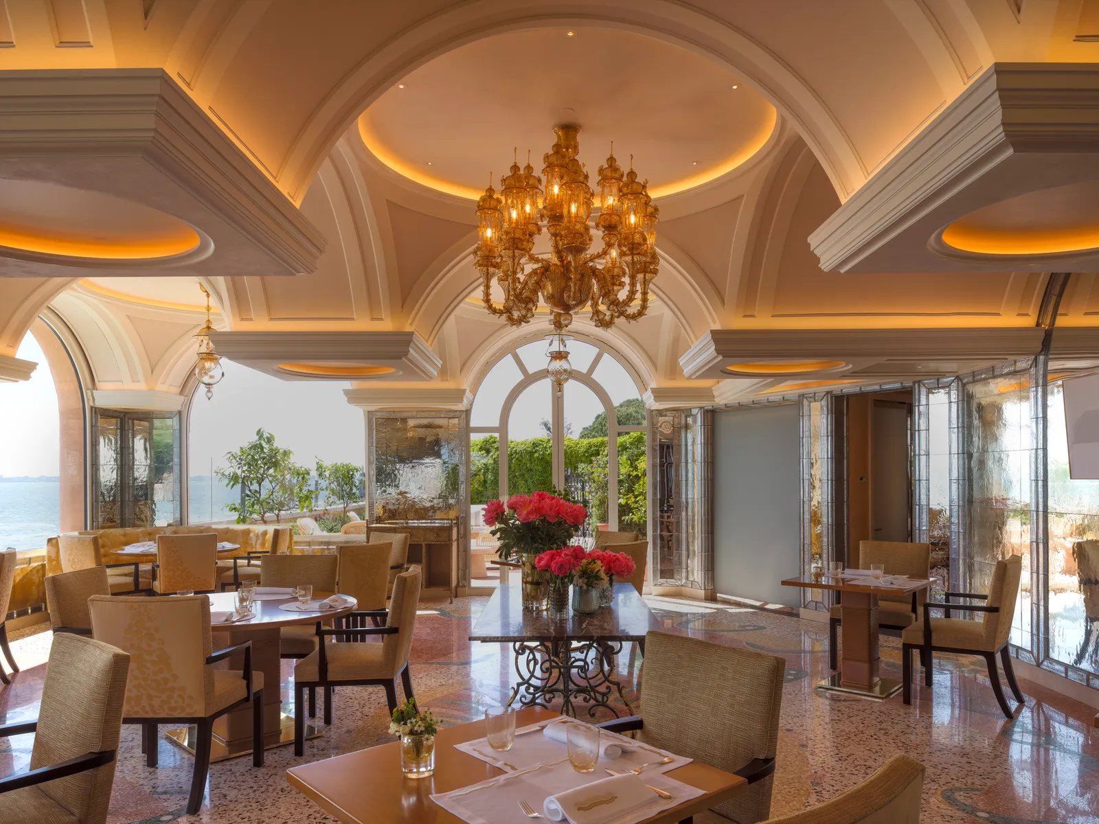 A dining room with gilded vaults, a Murano chandelier and arched windows onto the lagoon.