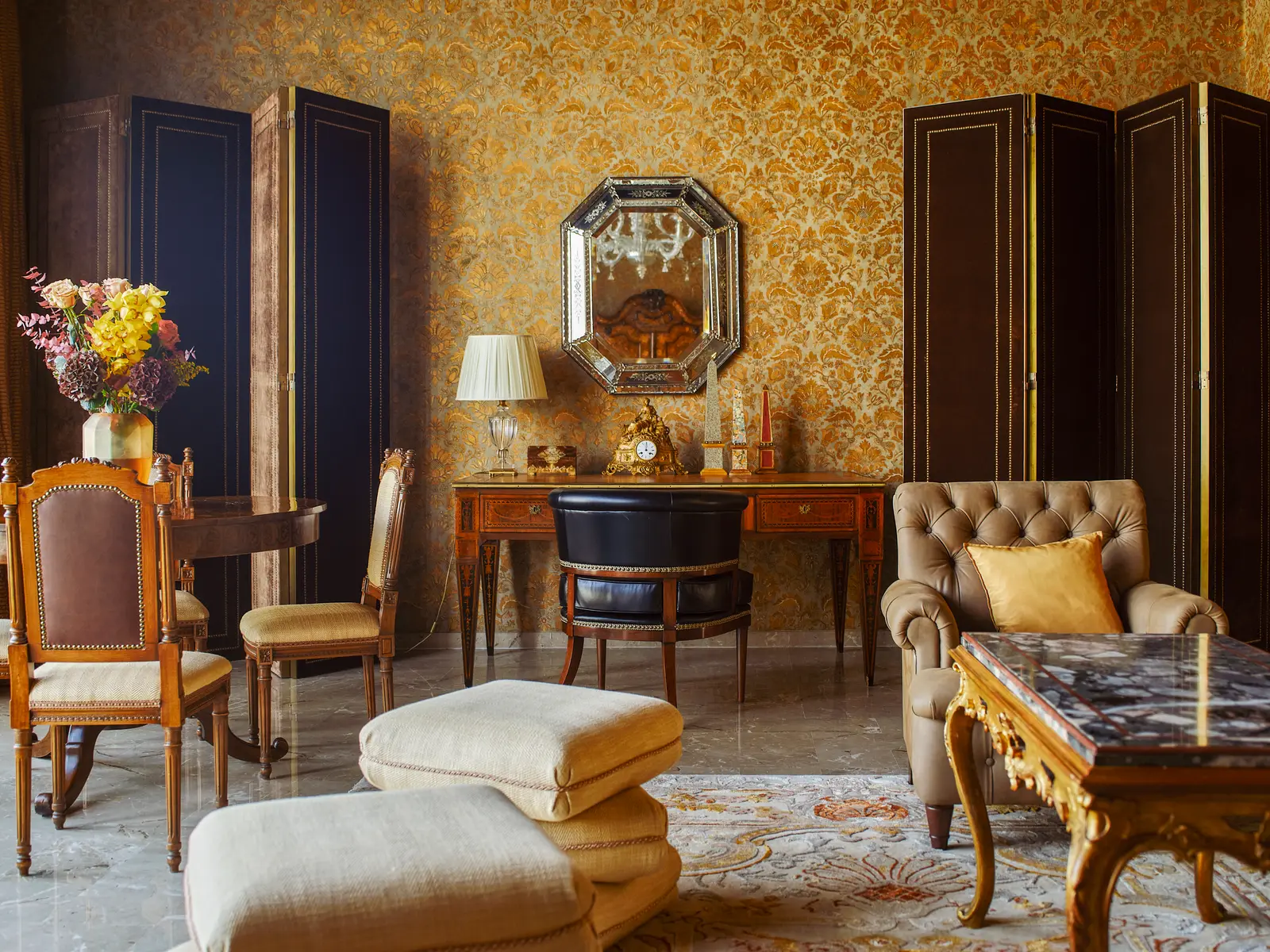 The Dogaressa Suite’s drawing room: gold damask walls, black lacquer screens, a writing desk and a buttoned armchair.