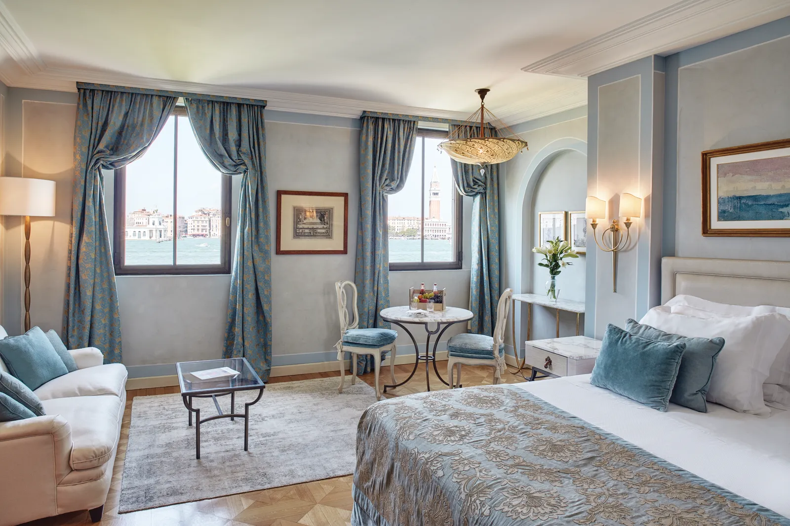 A room in Palazzo Vendramin with pale blue walls and 2 Gothic windows: across the lagoon, St Mark’s bell tower.