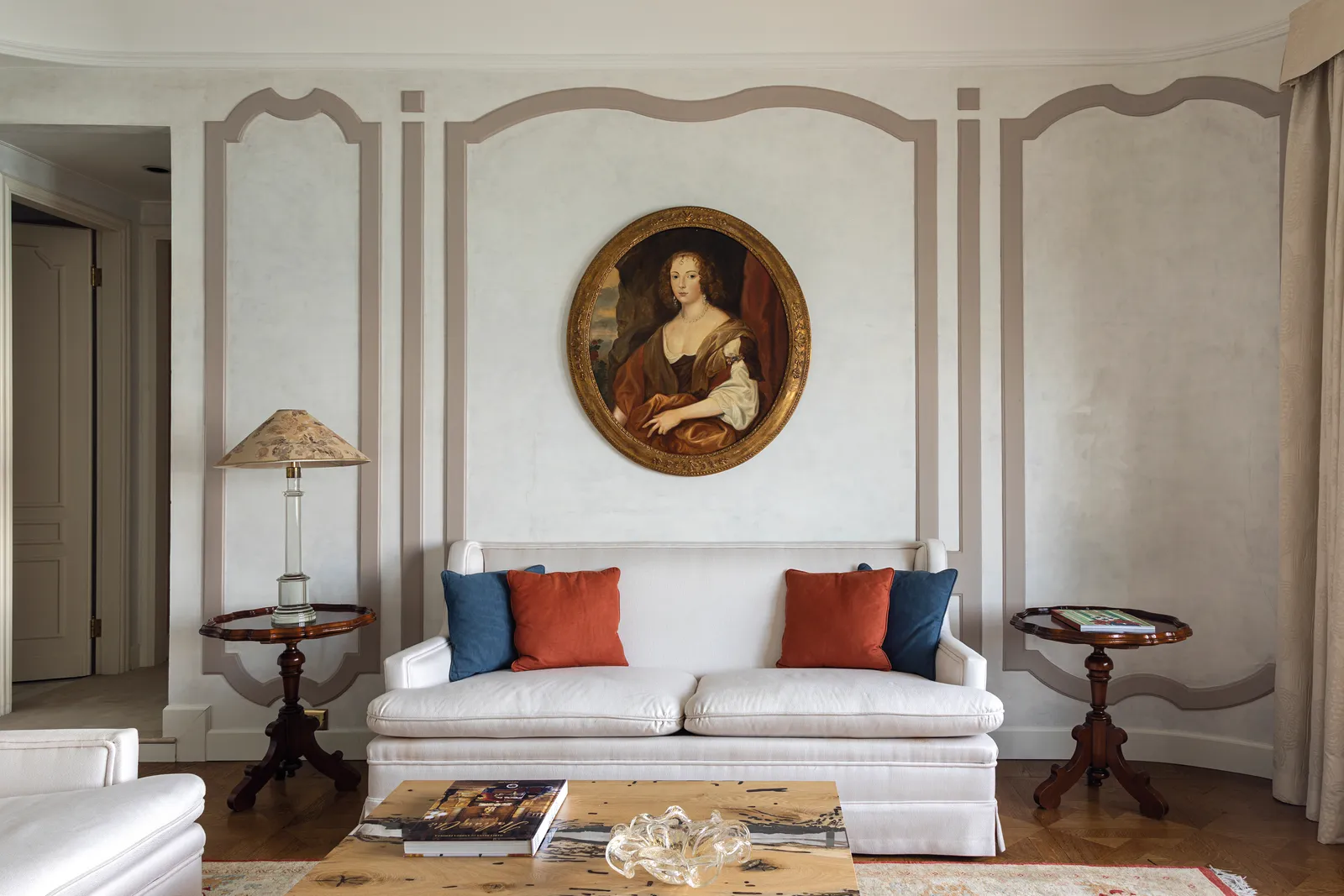 The sitting room of a suite in Palazzo Vendramin: a white sofa with red and blue cushions under an oval portrait, between grey panels.