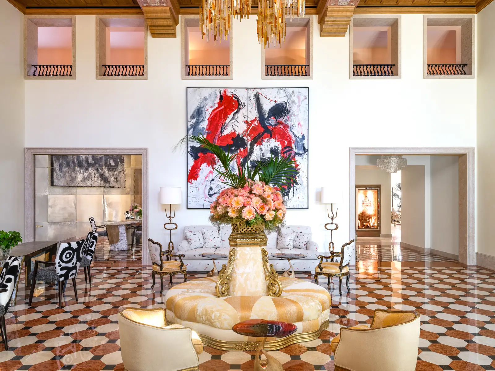 The double-height lobby: a floor of red and white hexagons, a large vase of flowers in the middle and a red abstract canvas on the wall.