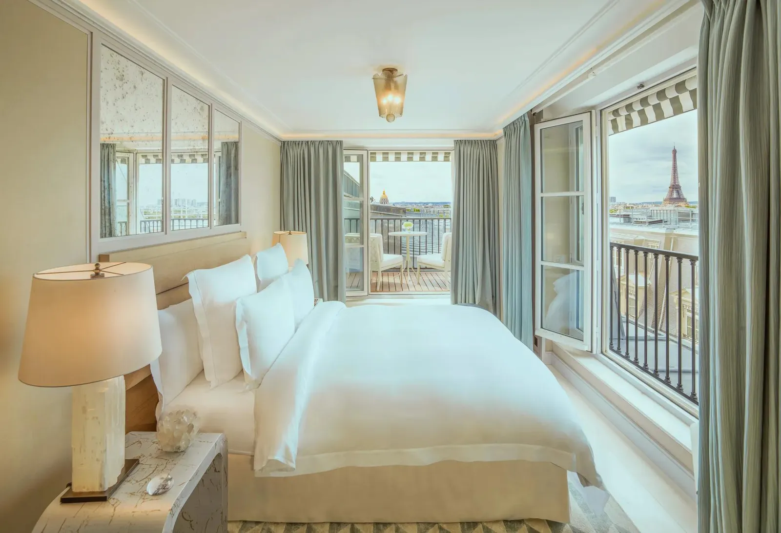 A bed and armchair beside a window with an Eiffel view