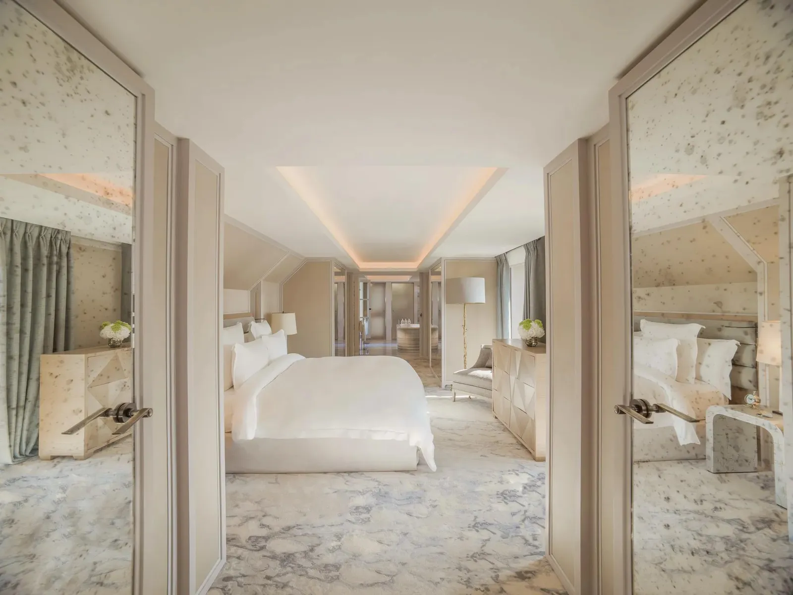 Pale bedroom with marble bathroom areas visible on either side