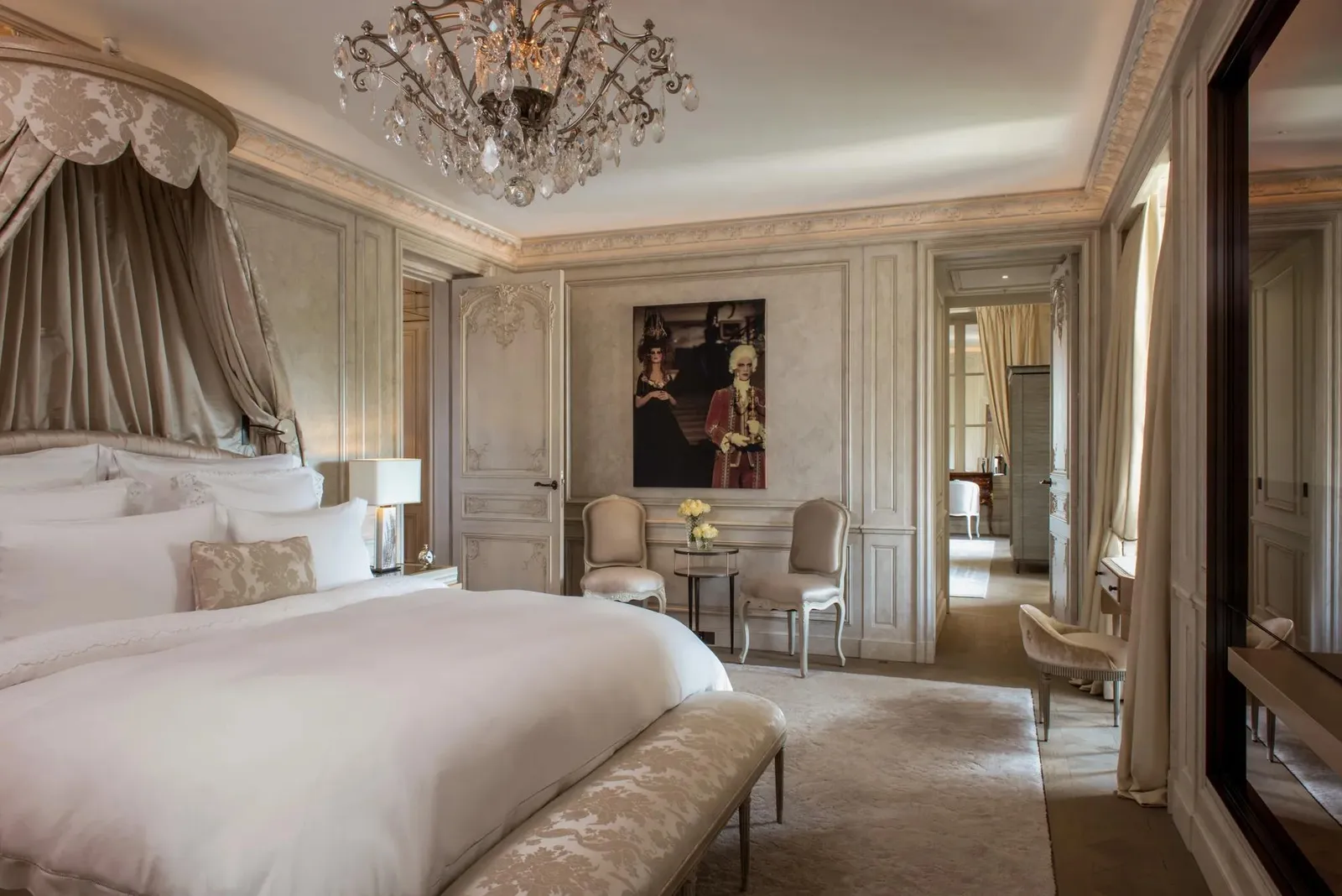 Pale bedroom with a bed, bench and chandelier