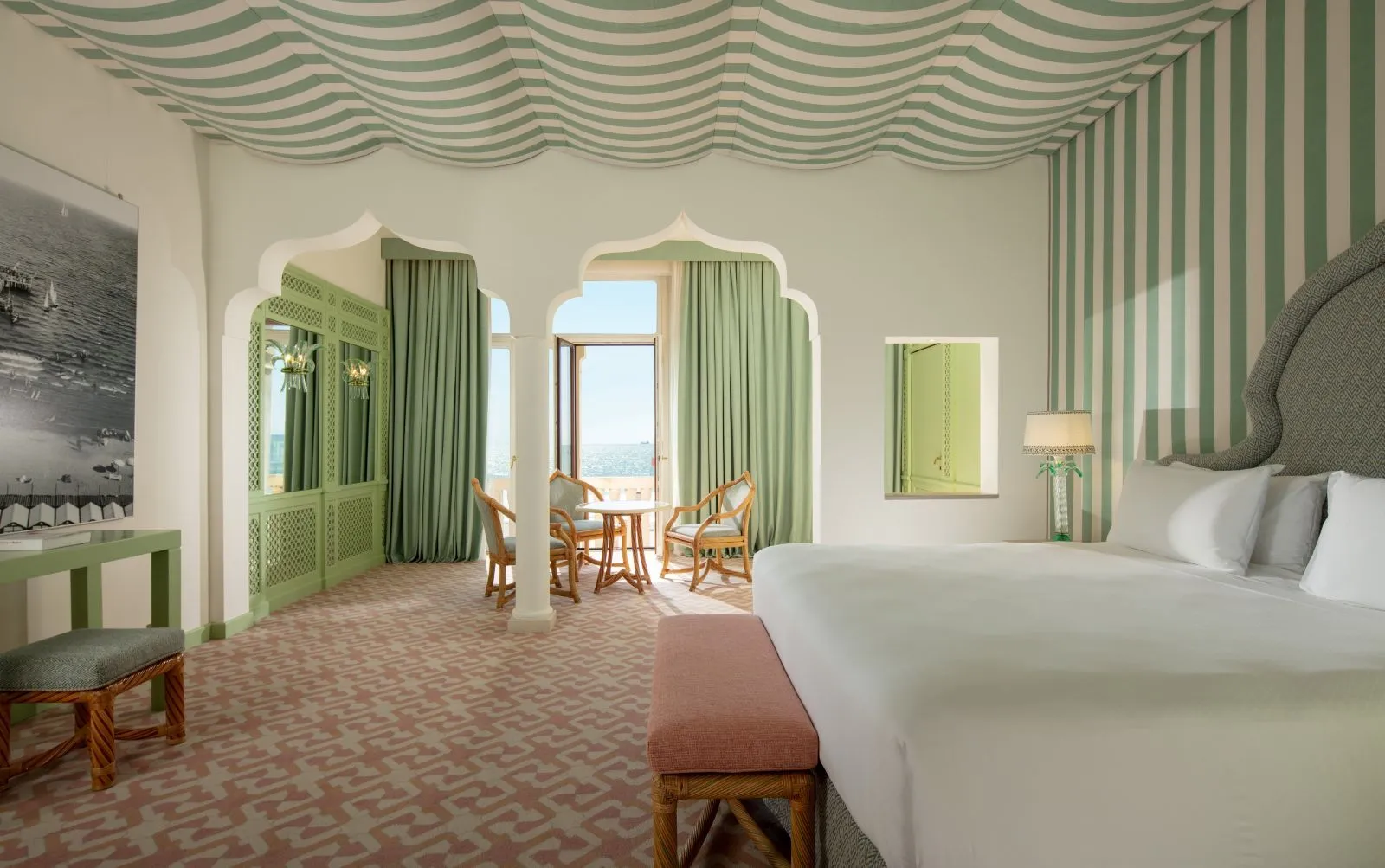 The Adriatic Suite’s bedroom: a green-striped tented ceiling, the bed and, beyond the arches, the sitting area with a French window onto the sea.