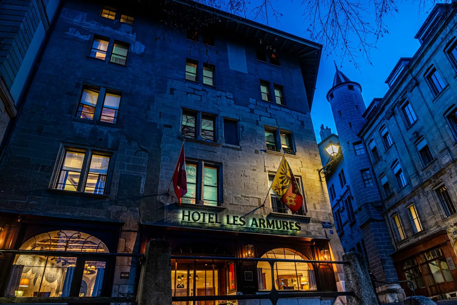 La facciata dell’hotel di sera, con l’insegna accesa nella città vecchia
