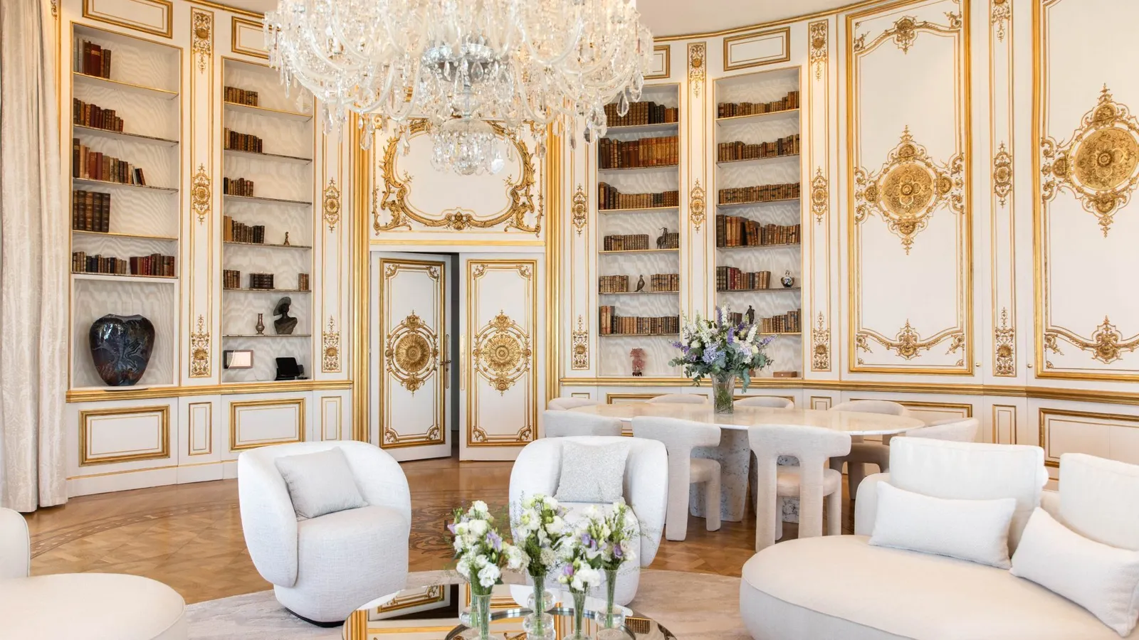 Il salotto della Penthouse Jeanne & Paul con librerie, boiserie chiare e lampadario