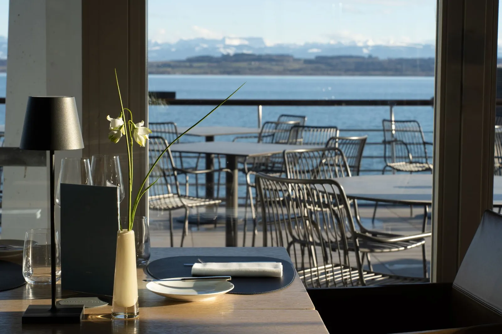 A table laid at La Table du Palafitte, with the lake and the Alps beyond the glass
