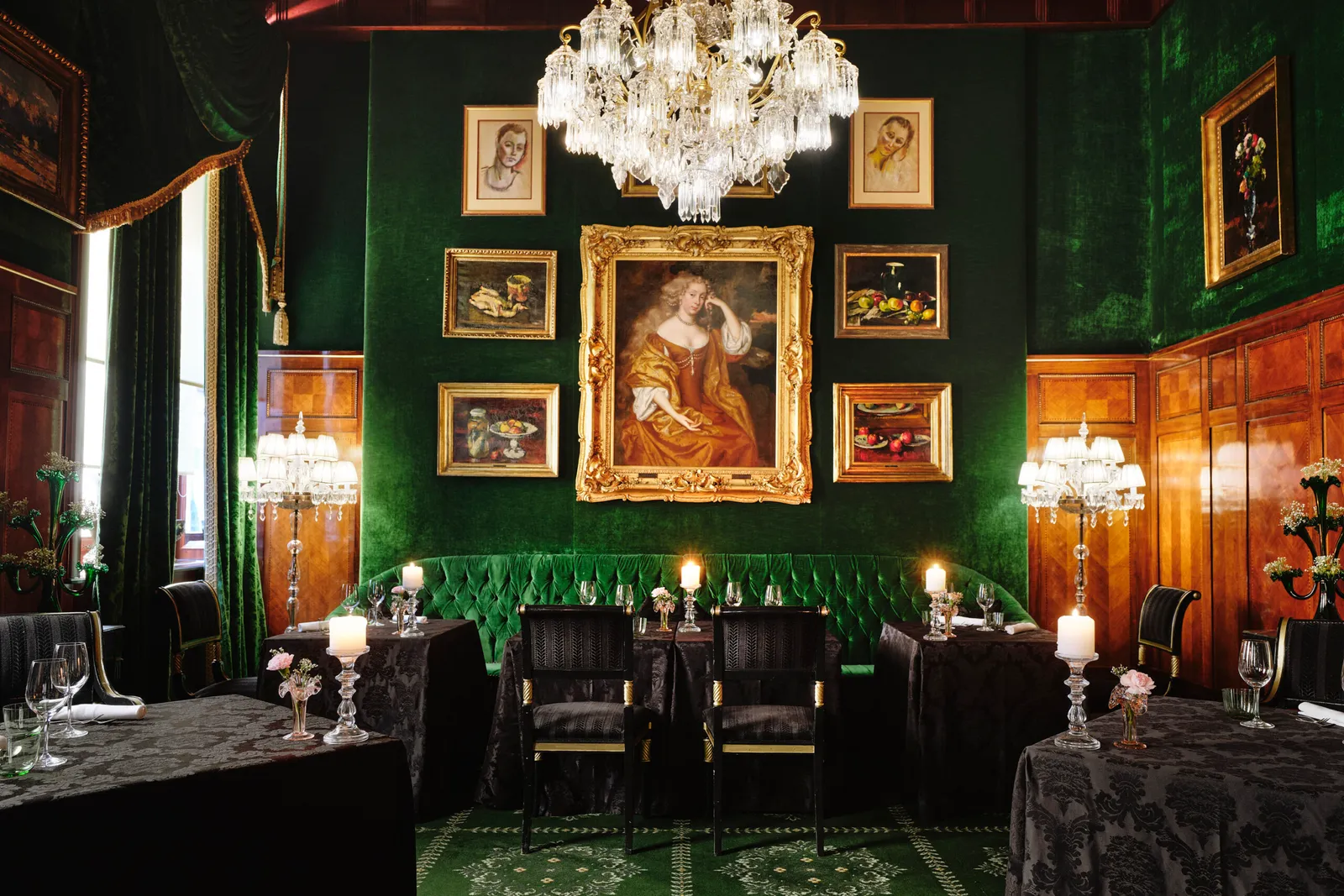 The Grüne Bar restaurant: green velvet walls, paintings in gilt frames, a crystal chandelier and candlelit tables.