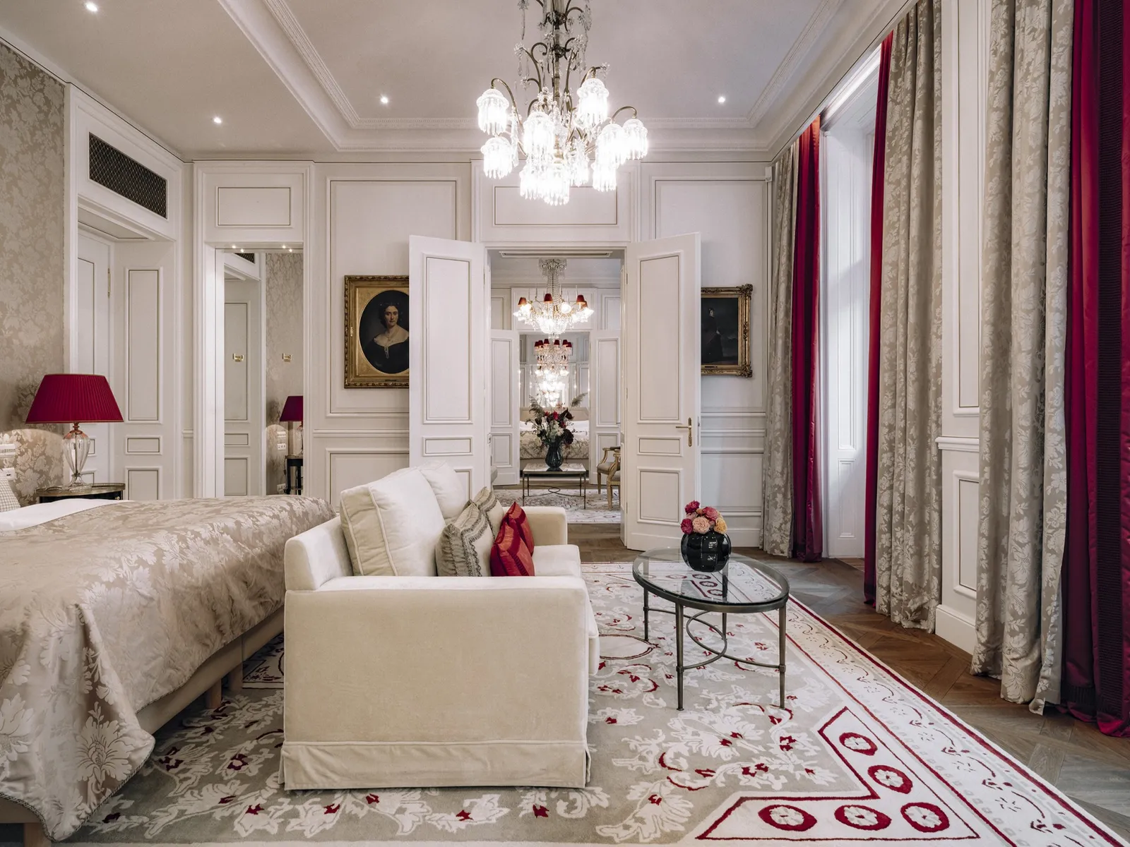 The Madame Butterfly Suite sitting room: a white sofa, a red-patterned carpet, wine-coloured curtains and a run of open doors.