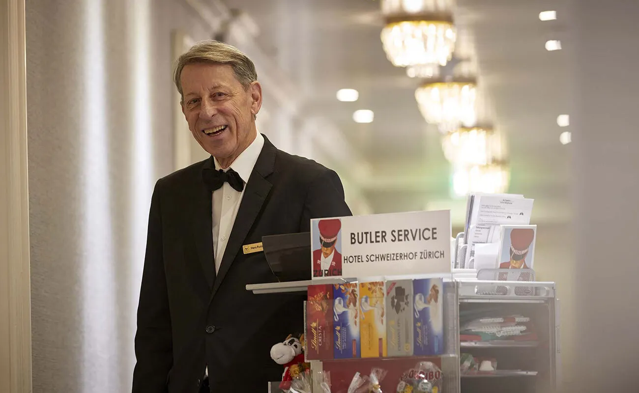 The butler with a trolley of chocolate and newspapers