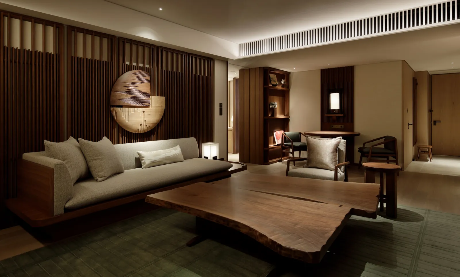 An Executive Suite’s living room: the long sofa, the live-edge table and the slatted wall with its wooden disc.