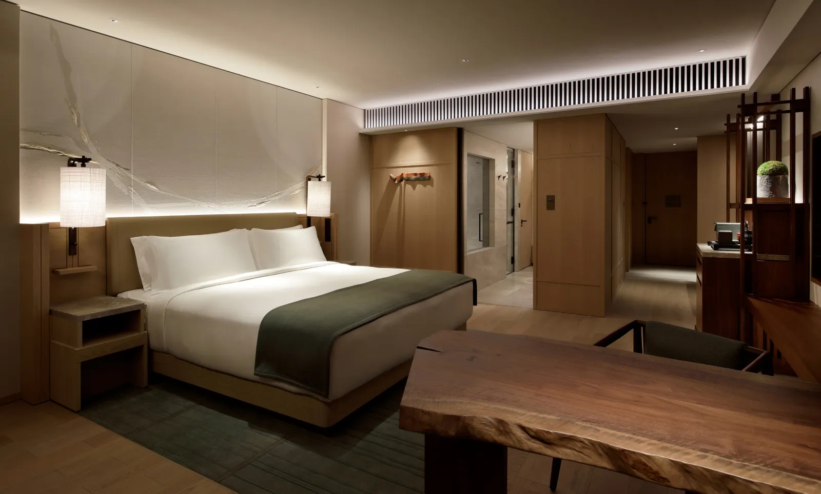 A Premier Room: the king bed, the live-edge wooden table in front and the dark timber shelves.