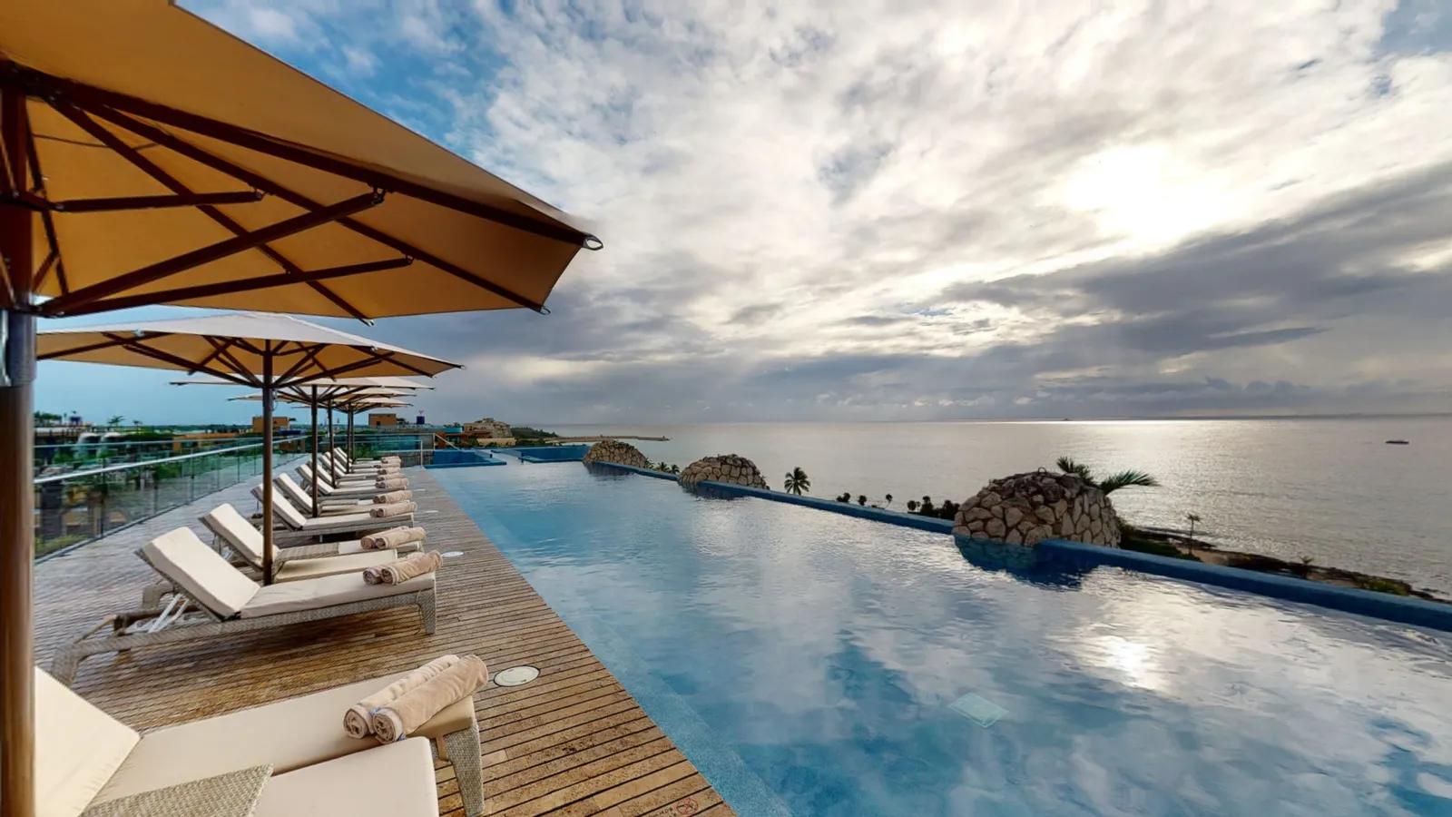 The rooftop infinity pool at Casa Fuego, with loungers, parasols and the sea