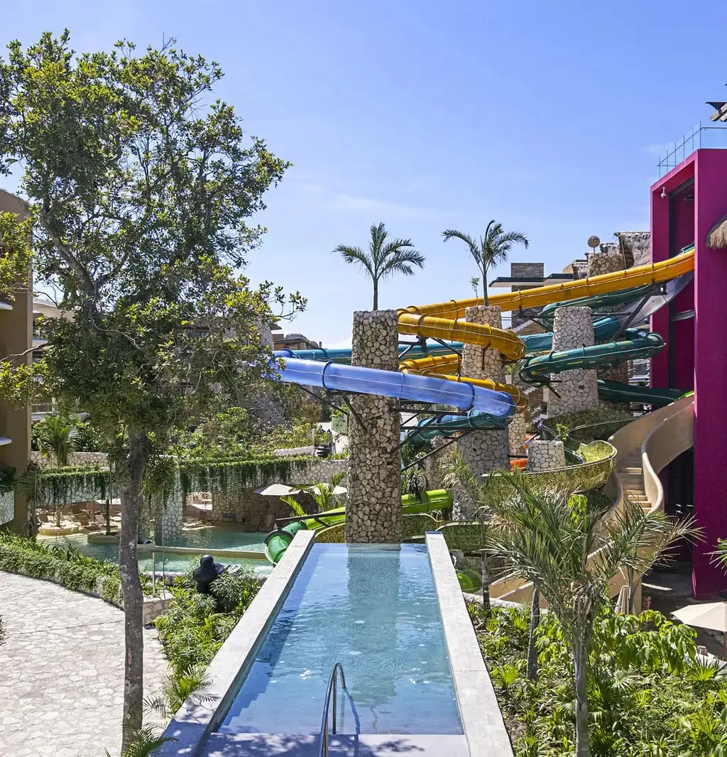 Colourful water slides among the palms, with a pool channel in the foreground