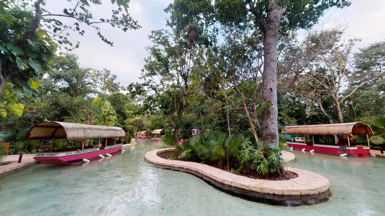 Trajineras moored on the river that runs through the resort, among trees and a planted island