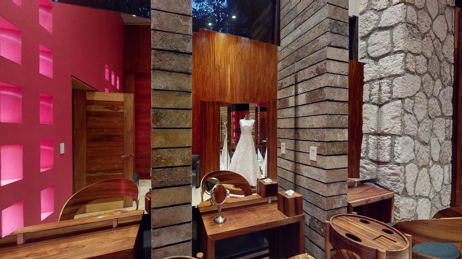 The Bridal Suite in the Muluk Spa: a wedding dress on a stand seen in a mirror, a wooden dressing table, stone columns and a pink wall with lit niches