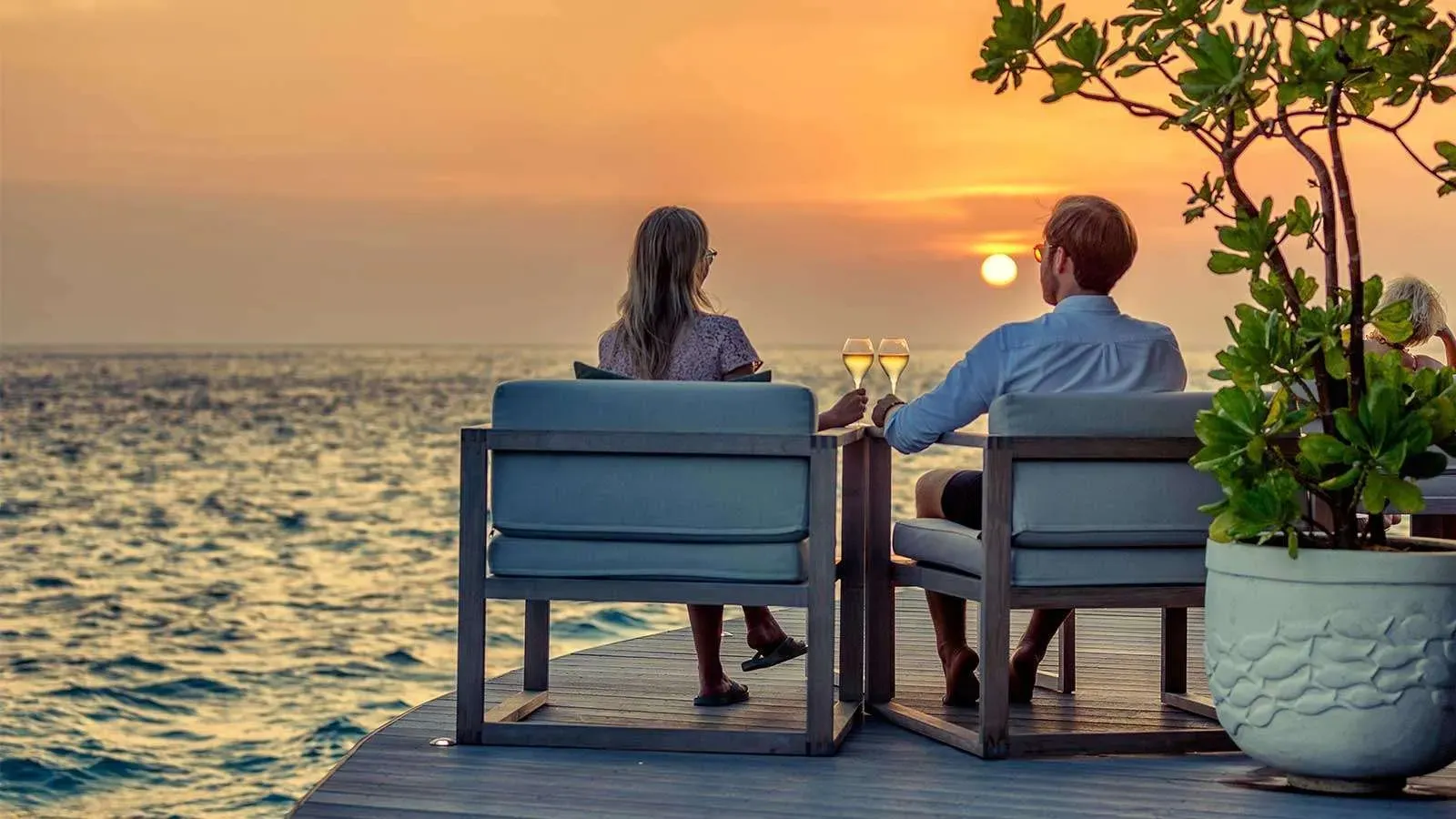 A couple at sunset on the Champagne Pavilion’s deck, over the water