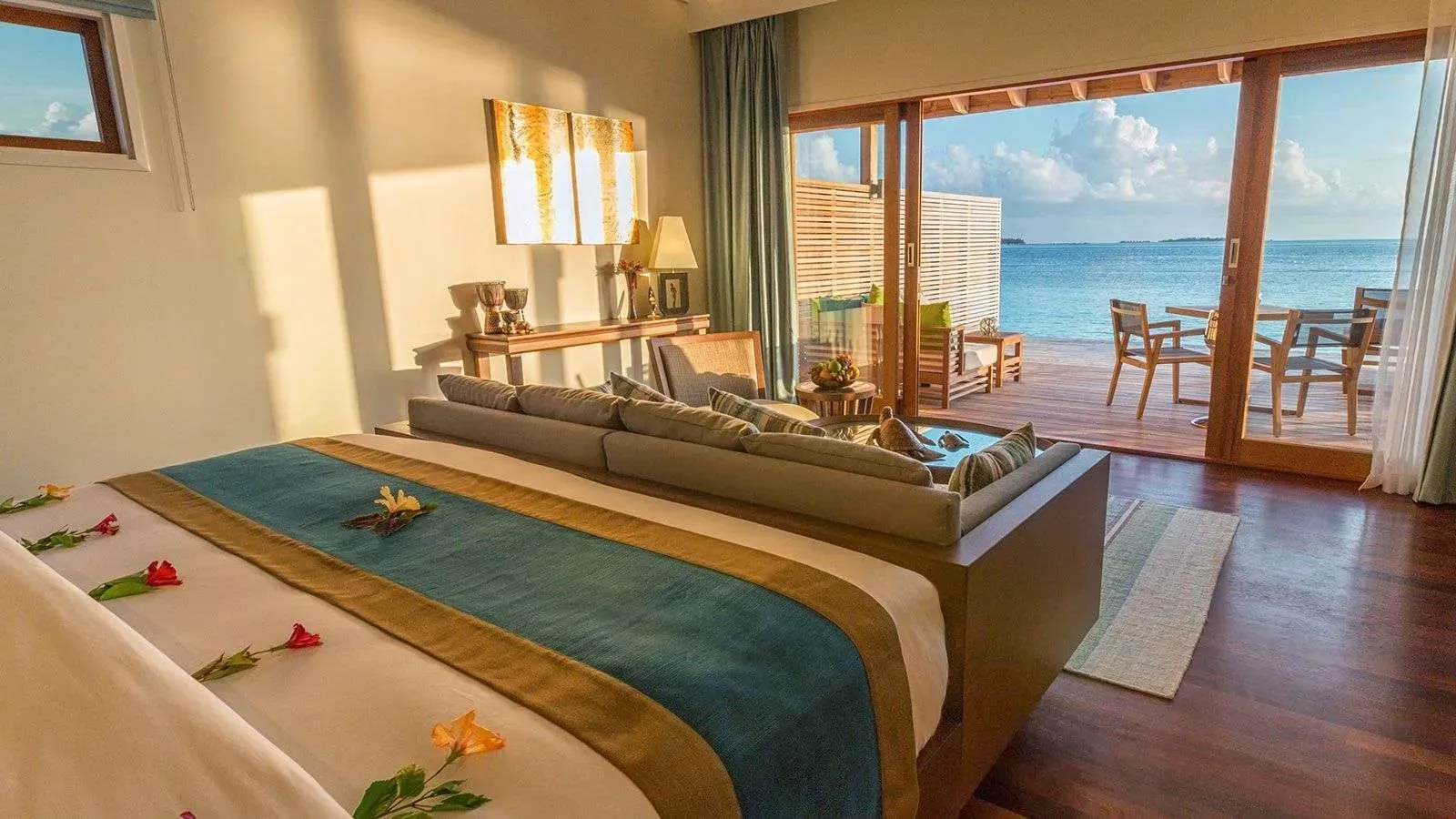 An Ocean Villa bedroom, its doors open to the deck and the lagoon