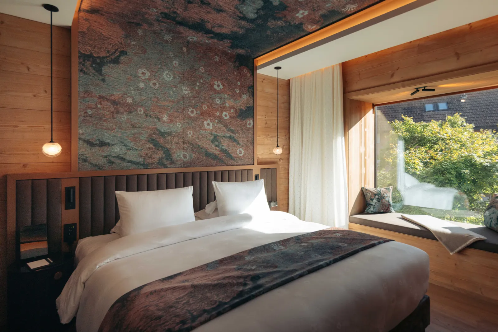 Il letto dell’Appenzell Suite sotto il tessuto dipinto, con la panca alla finestra