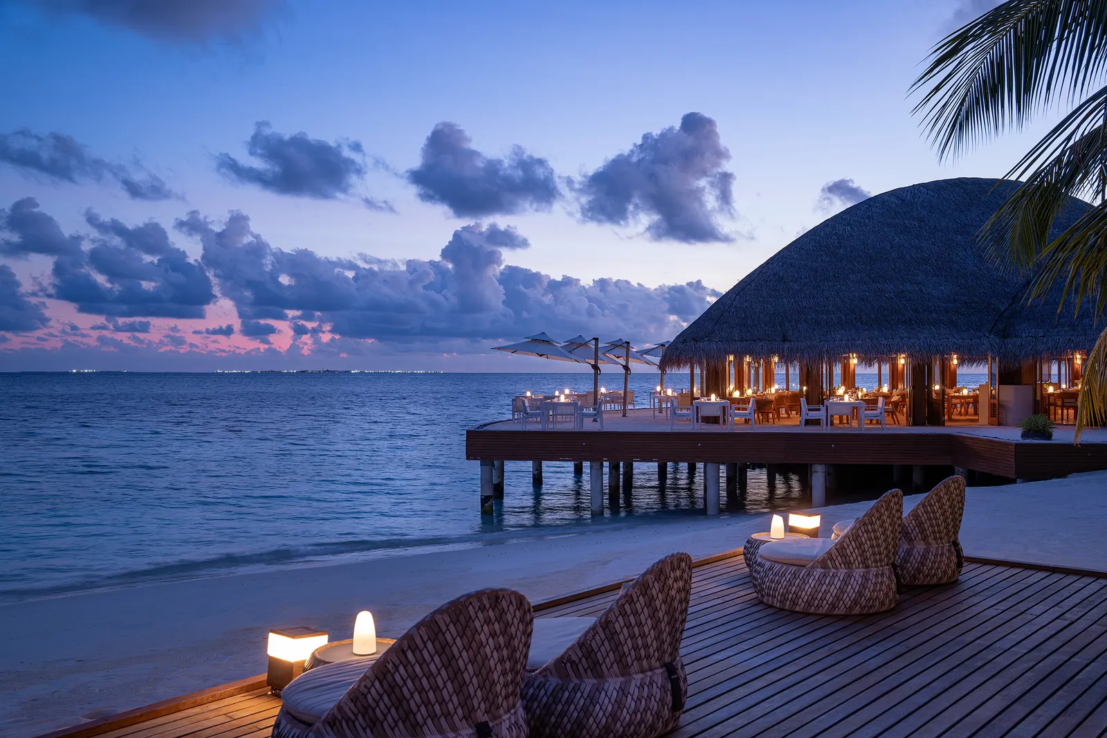 Celsius’ terrace over the water at dusk, lanterns lit