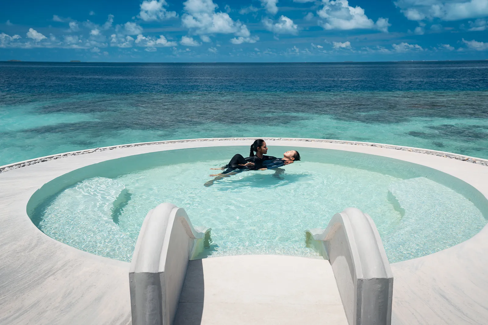 A guest floating in the Lonu Veyo, the round saltwater pool by the sea