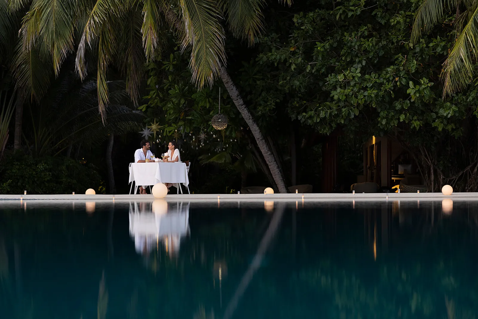 Dinner for 2 at the edge of the lit infinity pool, at night