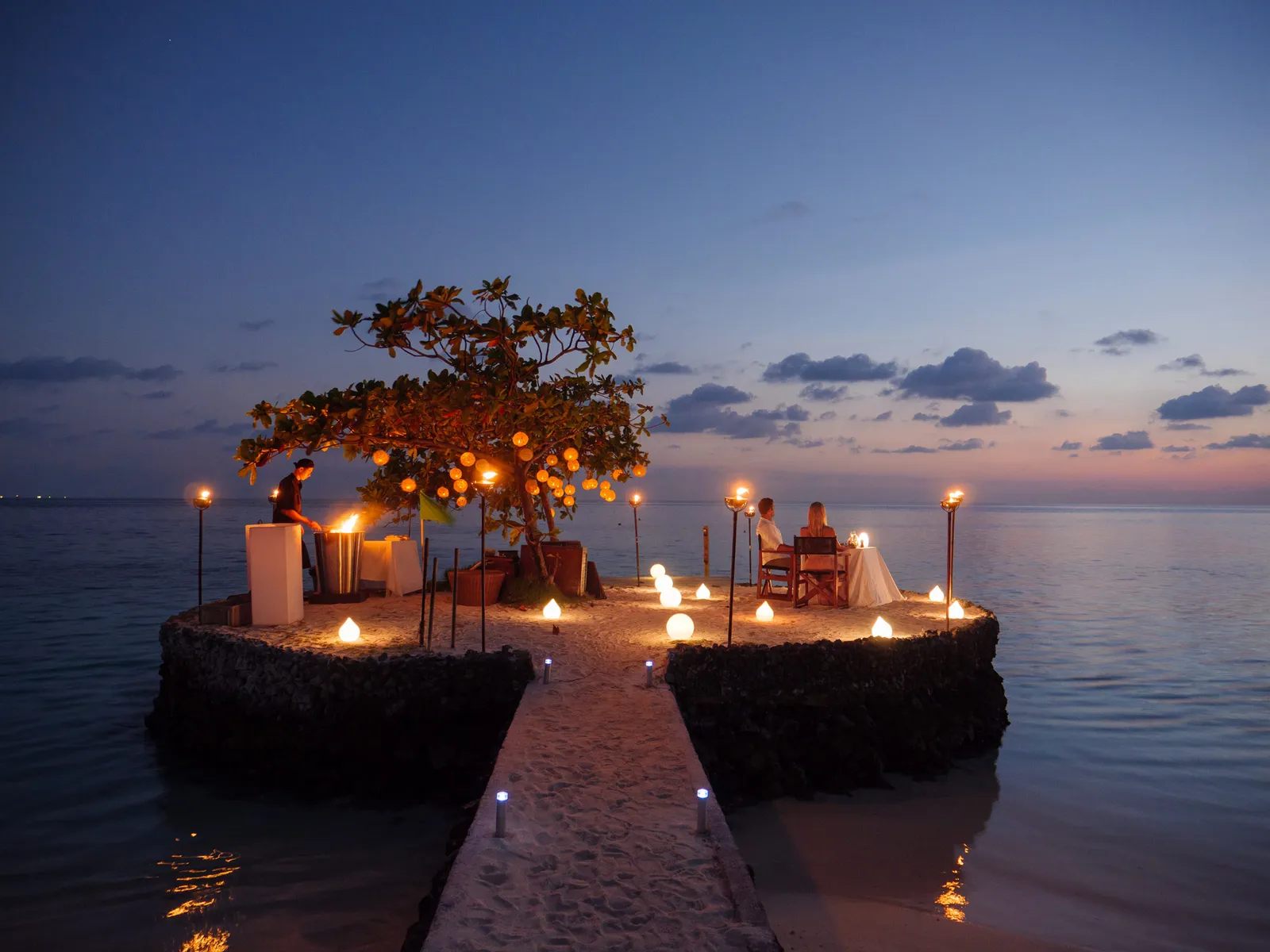 Dinner on a rock out at sea, reached by a lit walkway