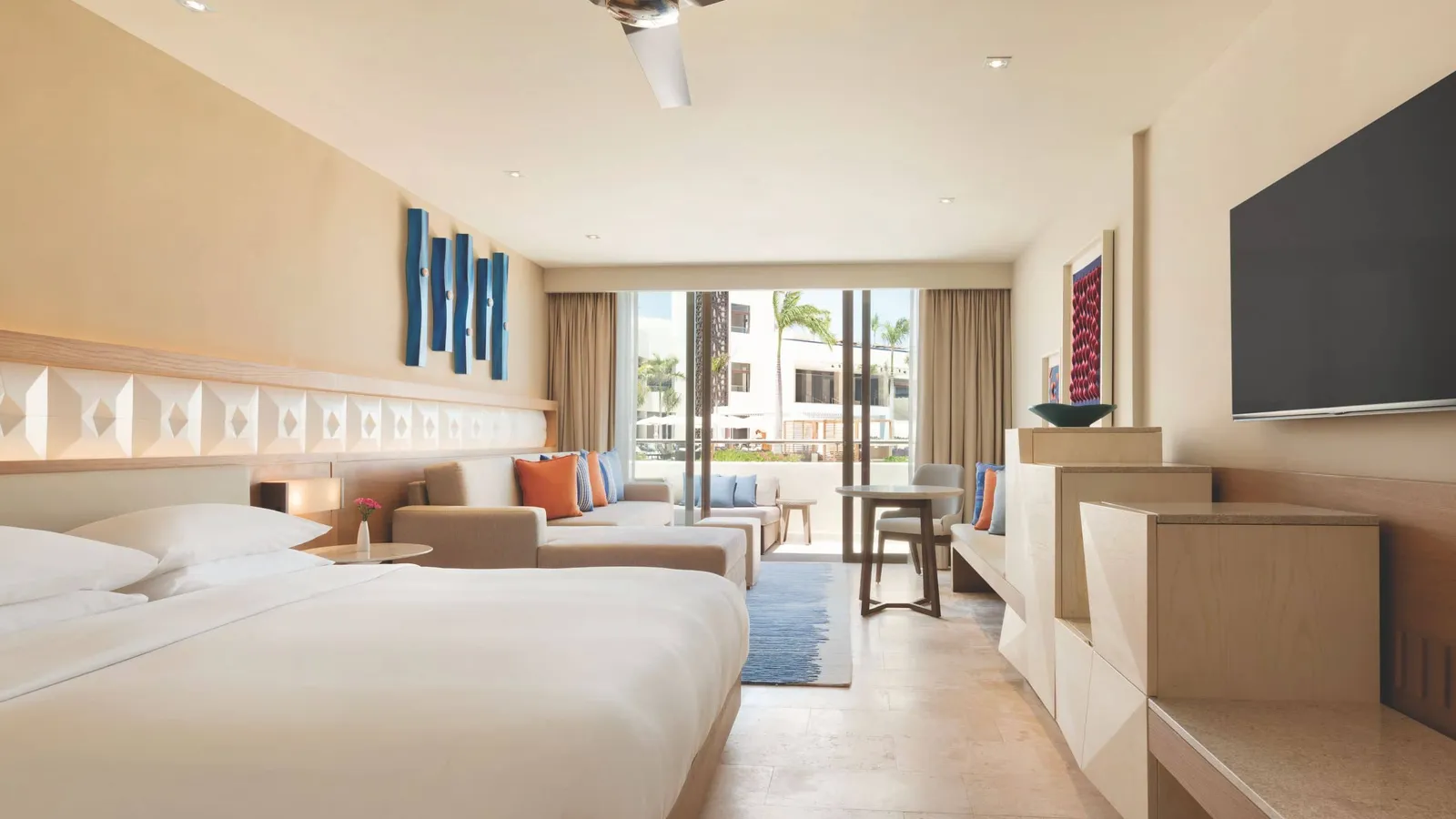 Beds, a sofa and a balcony in a resort room