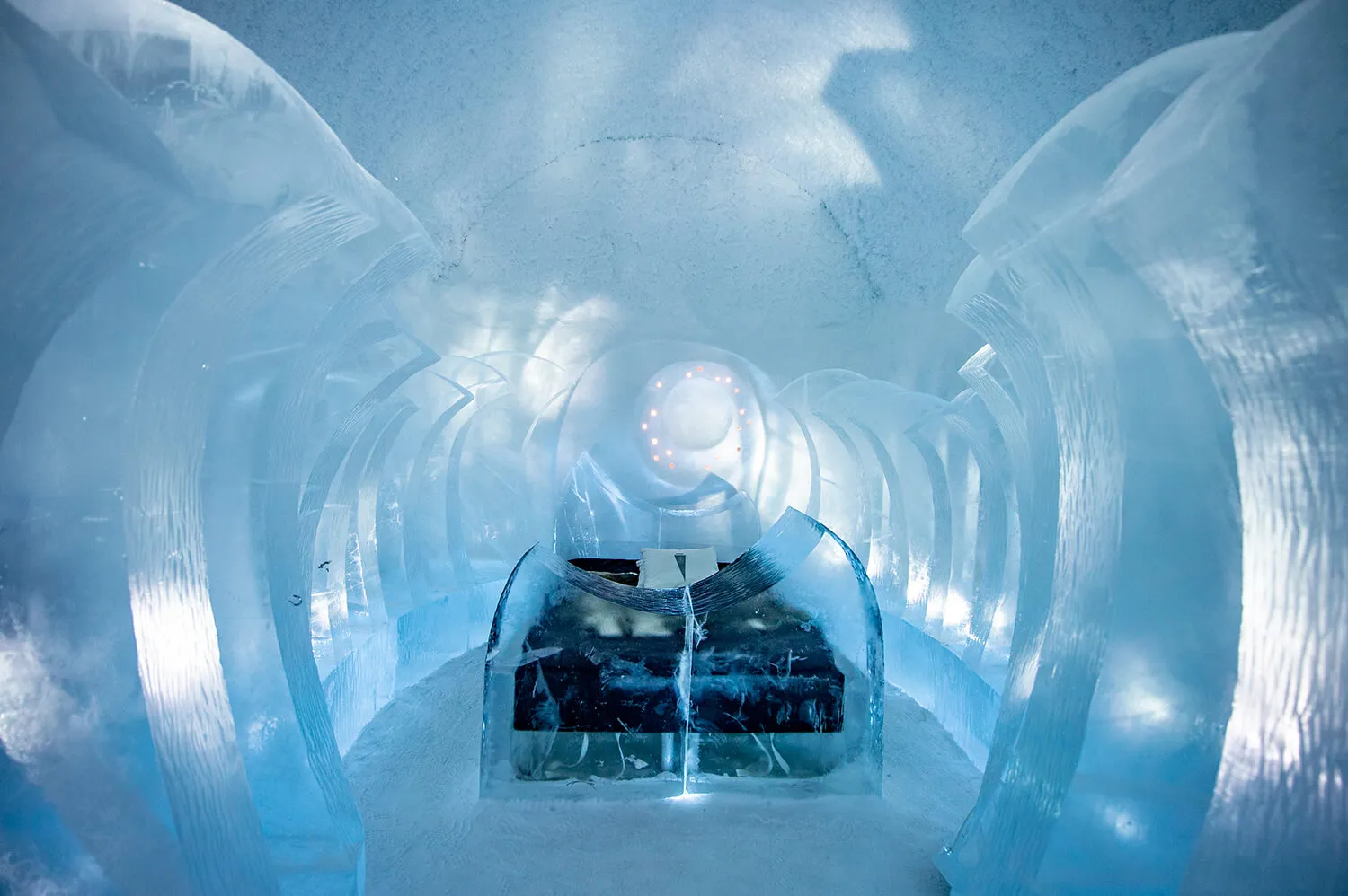 The Art Suite 365 Crescents: a path between tall curved blades of ice leads to the bed inside an ice arch, a ring of small lights on the wall behind.