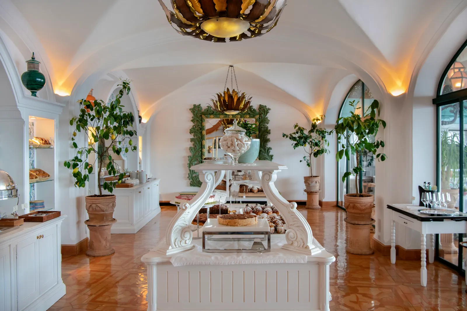 The breakfast buffet in the restaurant’s vaulted room, with potted lemon trees and the pastry table in the middle.