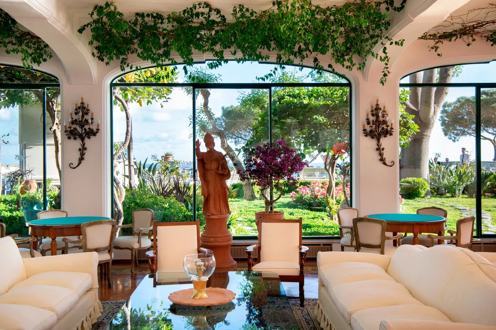 The lobby with vines running across the ceiling, pale sofas and arched windows onto the garden, around the statue of Saint Peter.