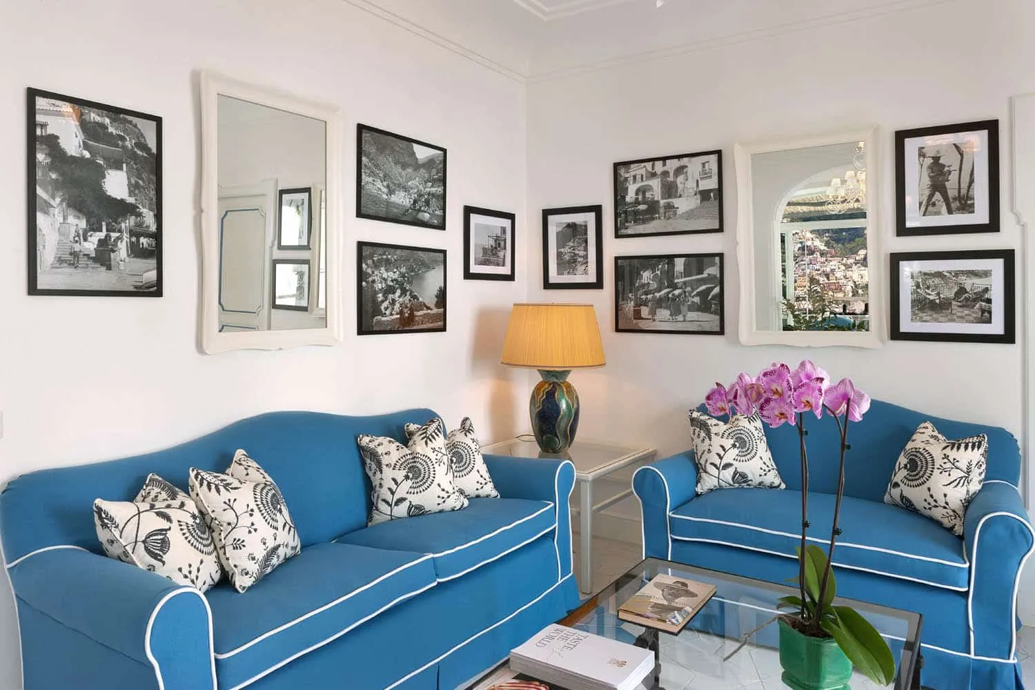 The sitting room of Carlino’s Prestige room, with 2 blue sofas and black-and-white photographs of old Positano on the walls.