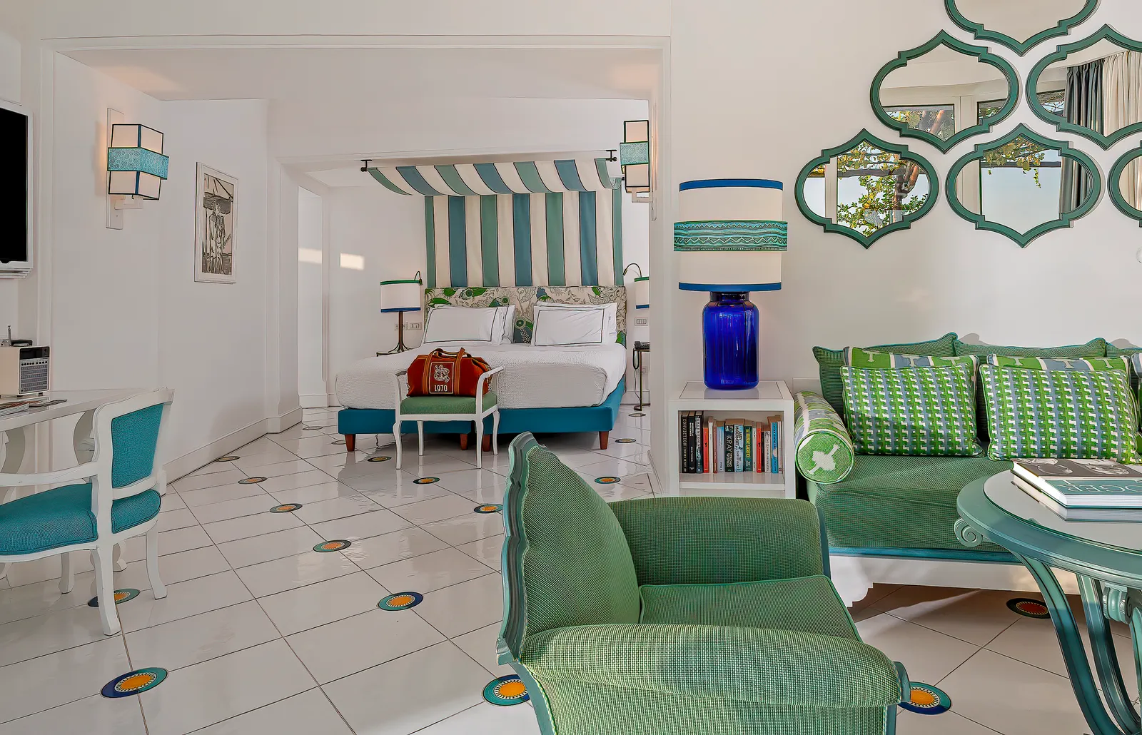A Prestige room with a green sitting area, Moorish mirrors on the wall and the bed under a striped canopy.