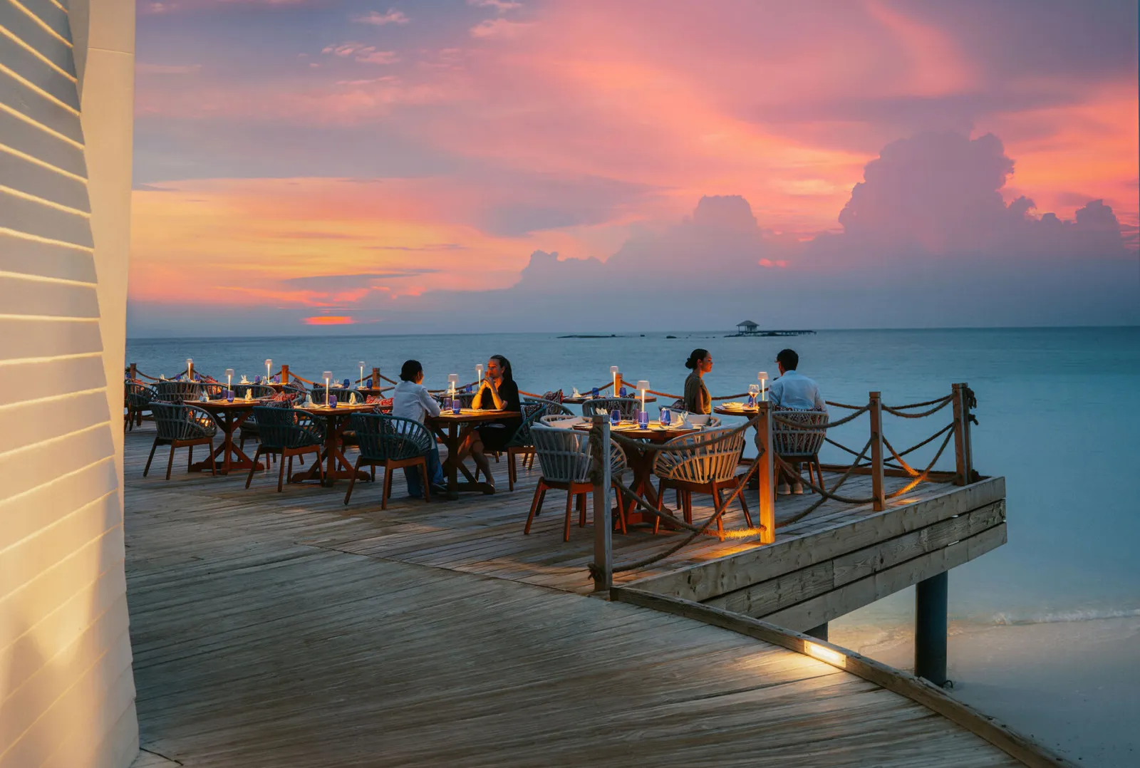 The Lighthouse’s deck over the water at sunset, tables laid and a few guests at dinner.