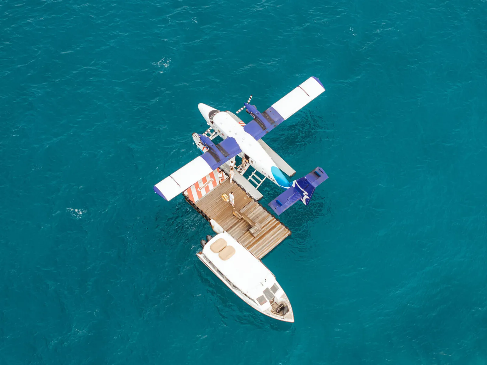 From above: the seaplane moored at the floating platform, a boat alongside.