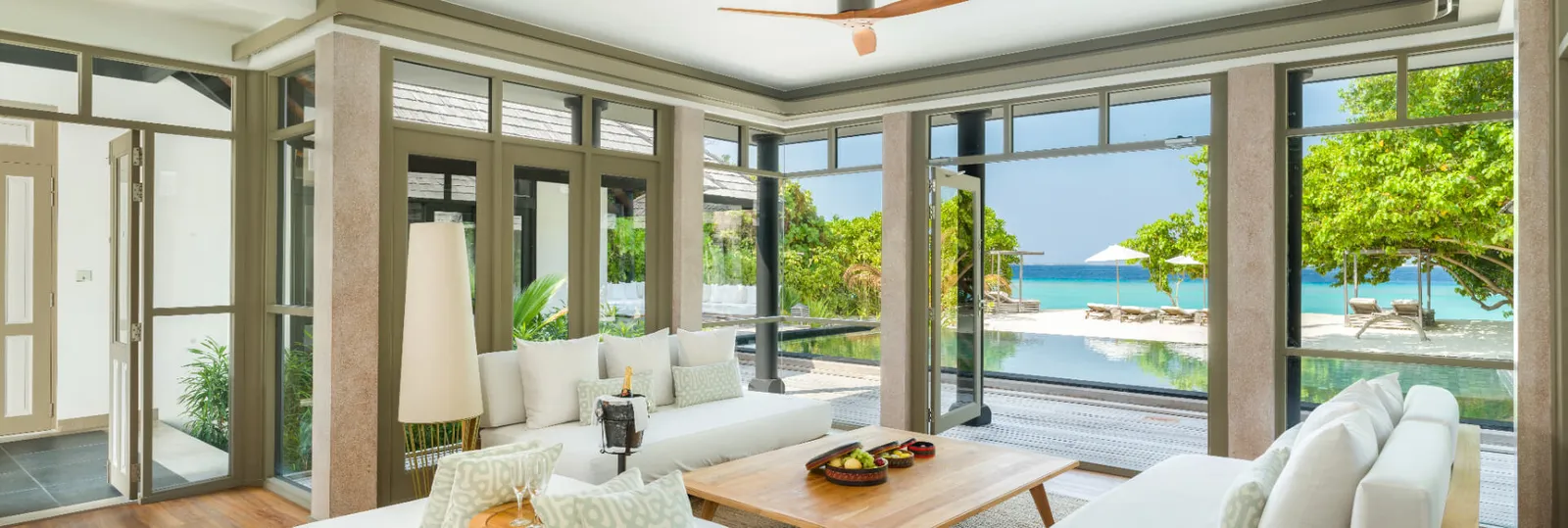The Manafaru Beach Residence living room with a white sofa and a beachfront pool.