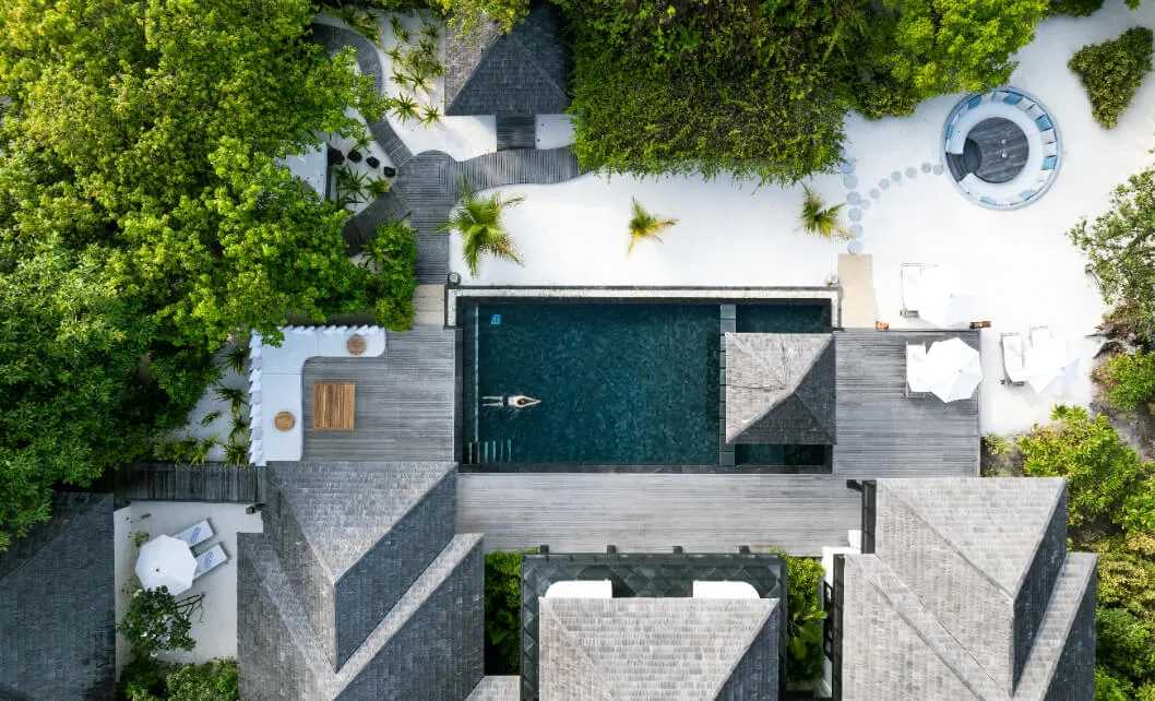 The Royal Beach Residence from above, with its pool and roofs among trees.