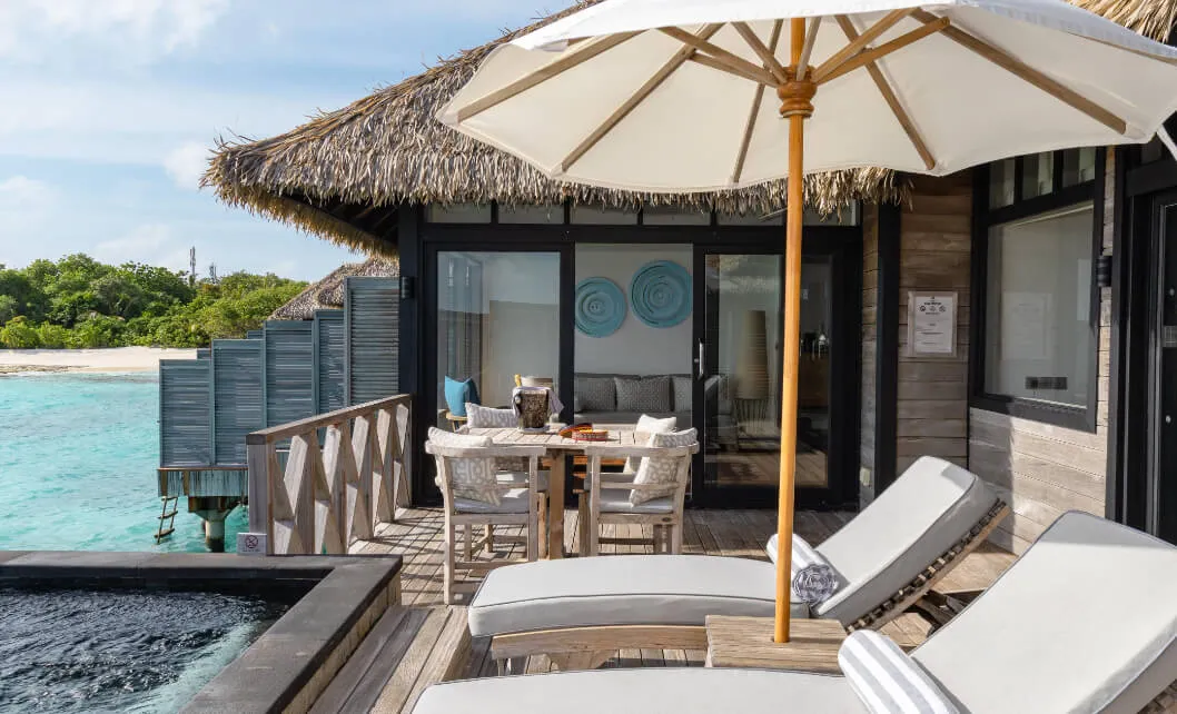 The Sunrise Water Villa deck with loungers, a parasol and a private pool.